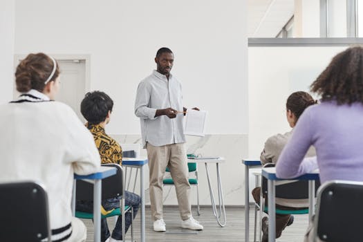 A diverse group of students learning in a classroom setting with attentive teacher.