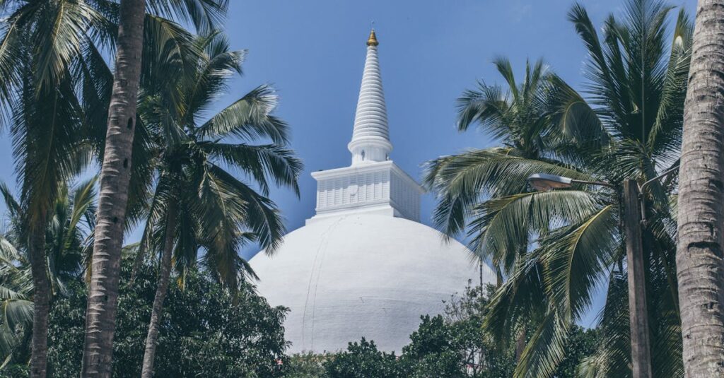 Serene view of the Mihintale Stupa amidst lush palm trees in Sri Lanka, under a clear blue sky.