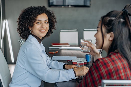 Two women engaged in a professional discussion in a modern office setting.