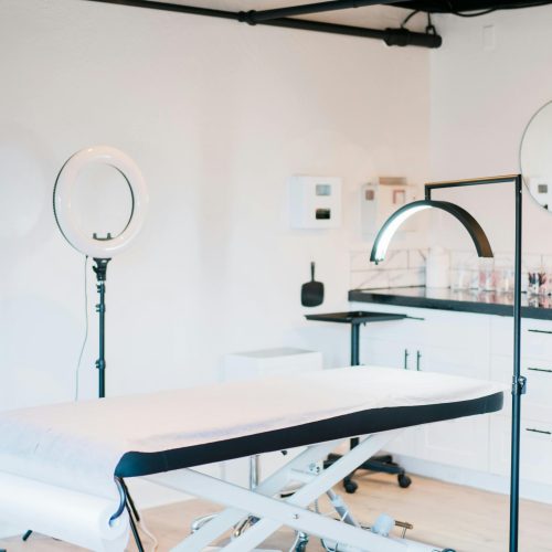 Bright and modern medical spa room featuring massage bed and studio lighting.