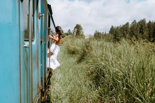 A woman in casual wear leans out of a train, surrounded by lush greenery and trees, capturing the spirit of travel and adventure.