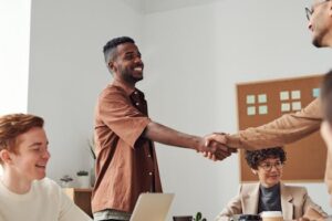 Business team members shaking hands during a meeting, demonstrating cooperation and teamwork.
