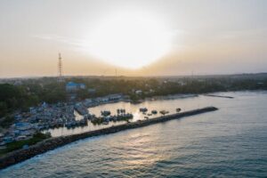 A stunning aerial view of a coastal harbor with boats docked during sunset.