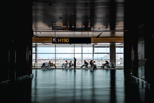 Silhouetted travelers waiting at Shanghai airport terminal gate H190 with cityscape view.
